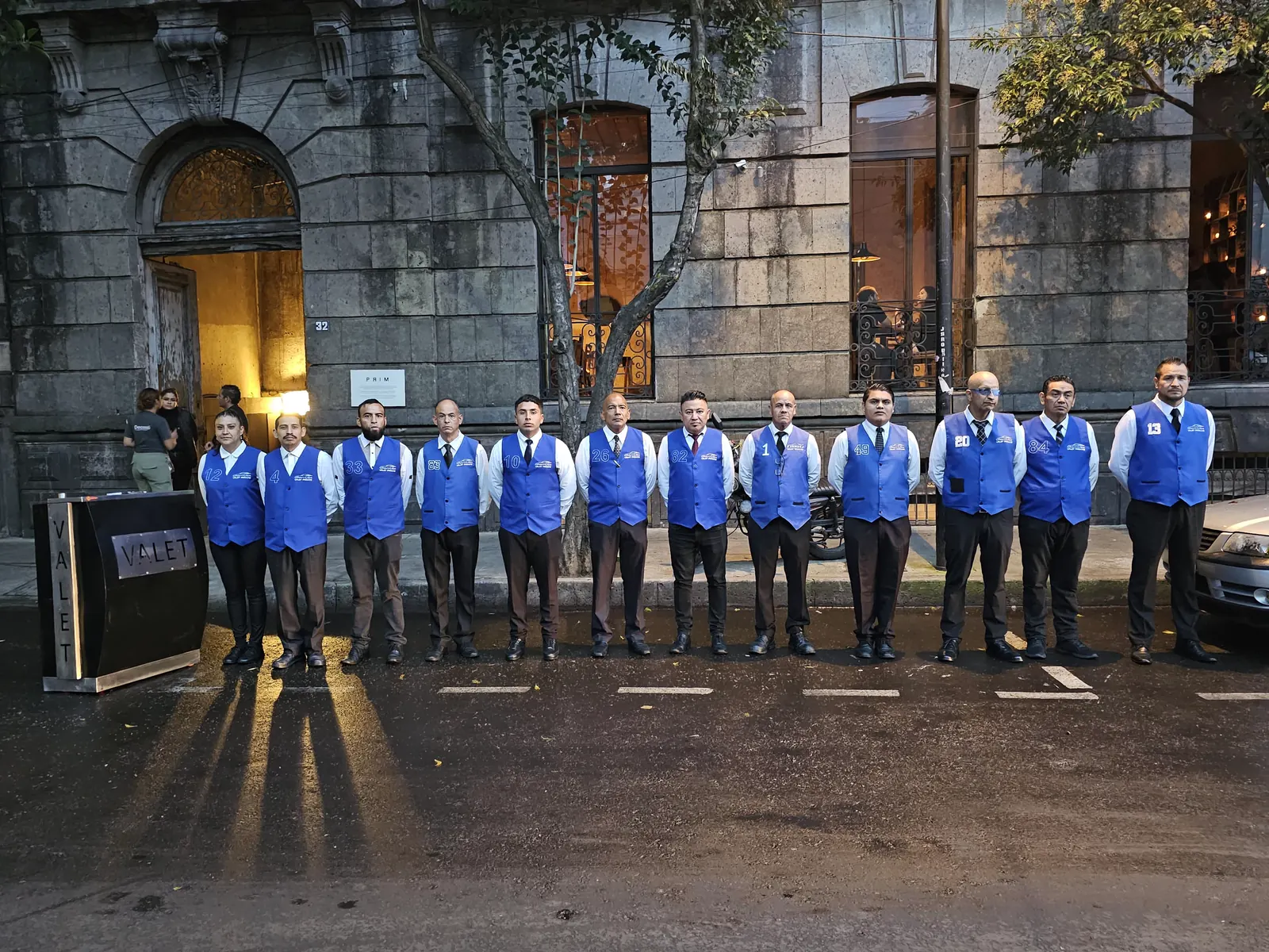 Equipo de valet uniformado formado en una calle durante un turno al anochecer